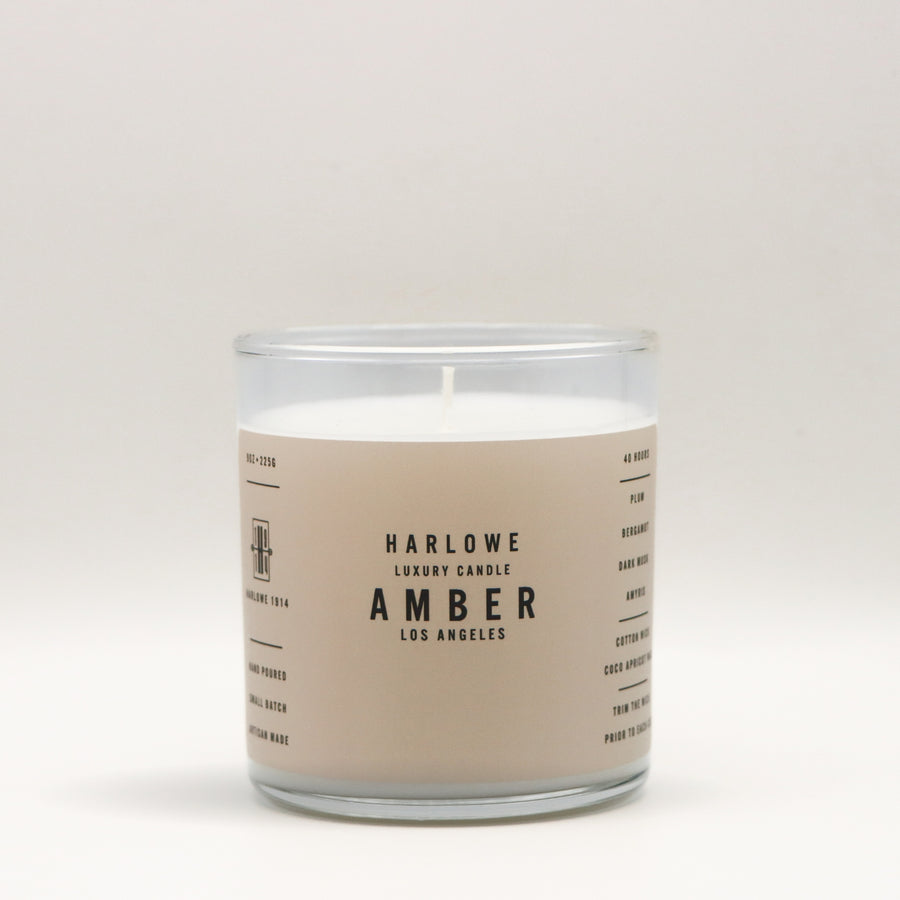 Harlowe Luxury Candle with Amber 
 label on a beige background
